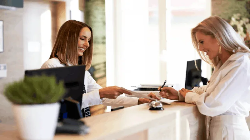 Loyal salon client checking in at the front desk for a repeat appointment